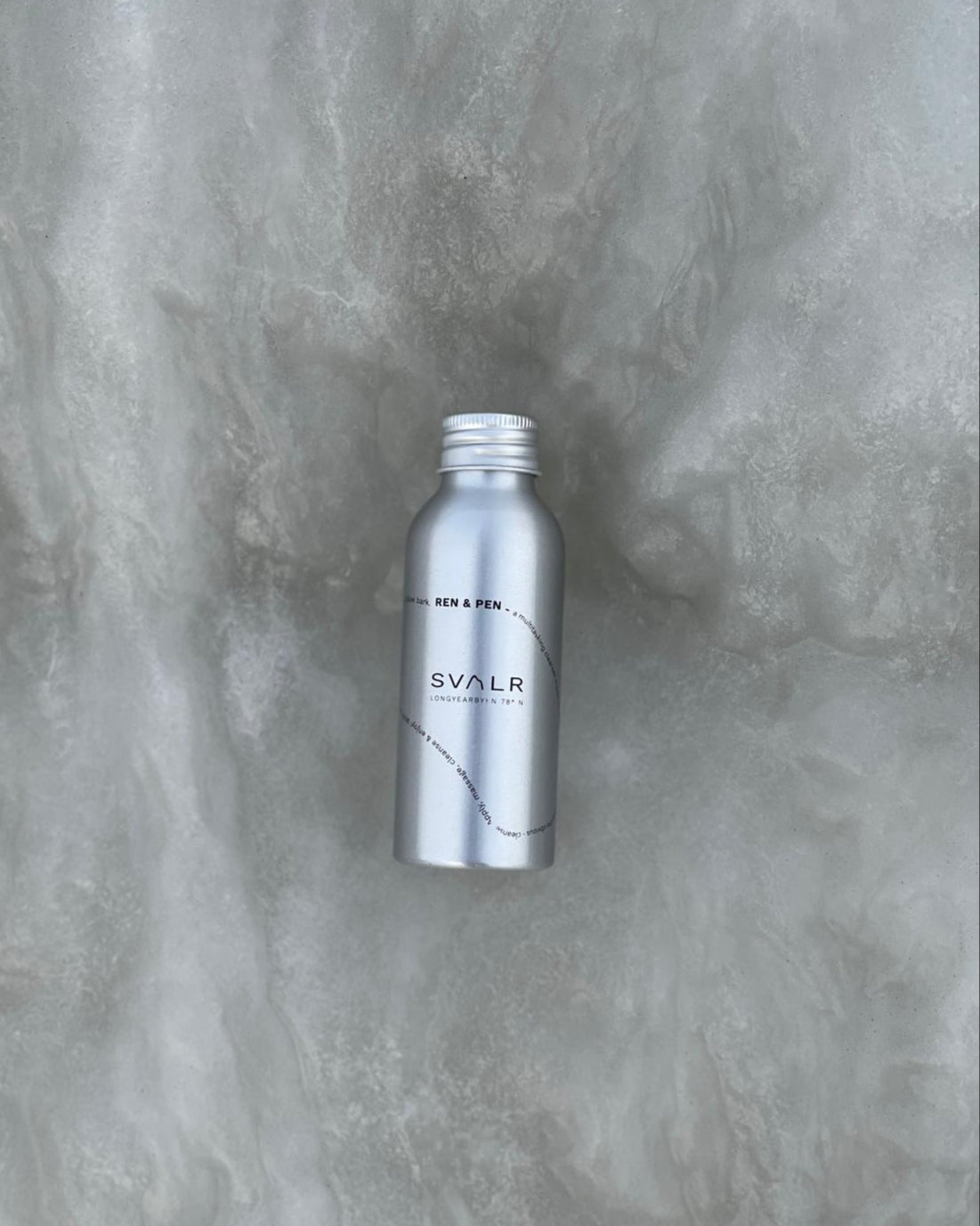 Silver bottle with 'SVALR' branding on a textured gray background